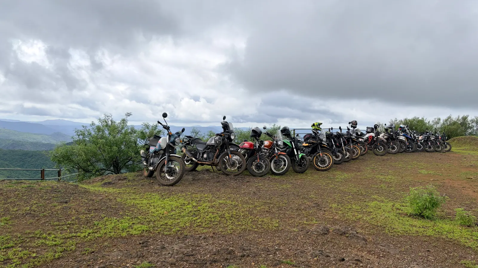 A line of motorcycles parked at a hilltop viewpoint overlooking the lush Western Ghats under dramatic monsoon skies.