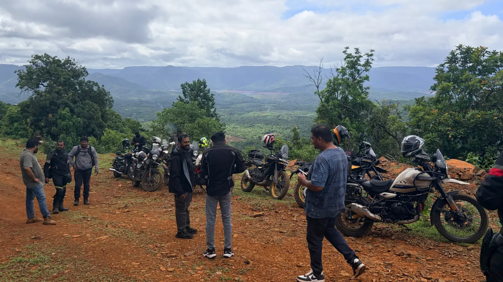 Riders gather beside their parked motorcycles at a scenic viewpoint overlooking the Western Ghats during a break in the ride.