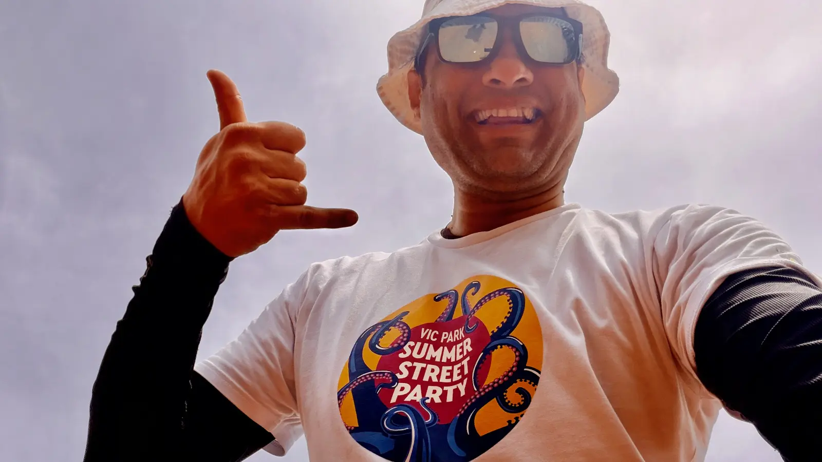 Alan smiling into the camera before the ride wearing a bucket hat and sunglasses on a bright day.