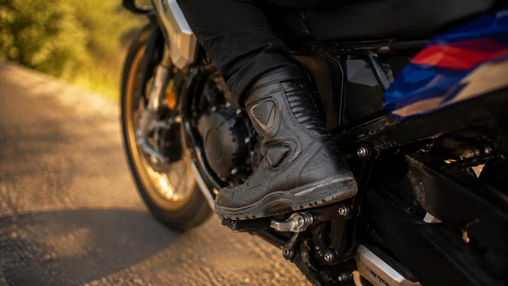 Two riders wearing different footwear beside their motorcycles